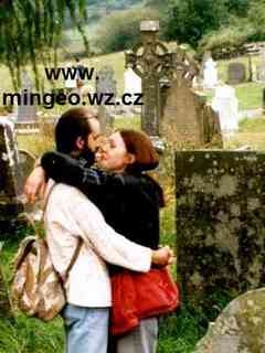 Mladá žena a muž se objímají na hřbitově